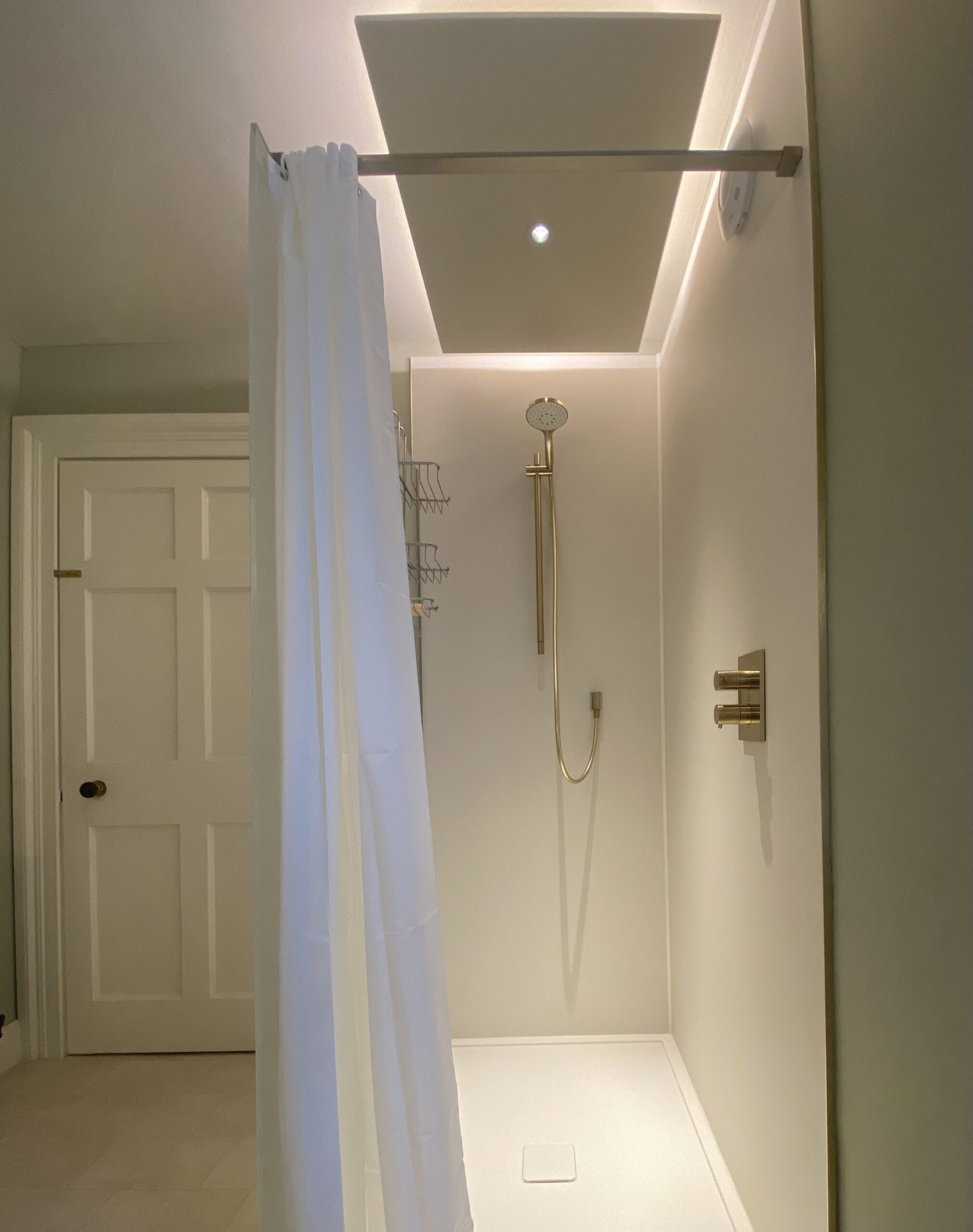 5 tips for lighting a bathroom. A photo of an illuminated modern white shower cubicle in a domestic bathroom, specialist lighting designer