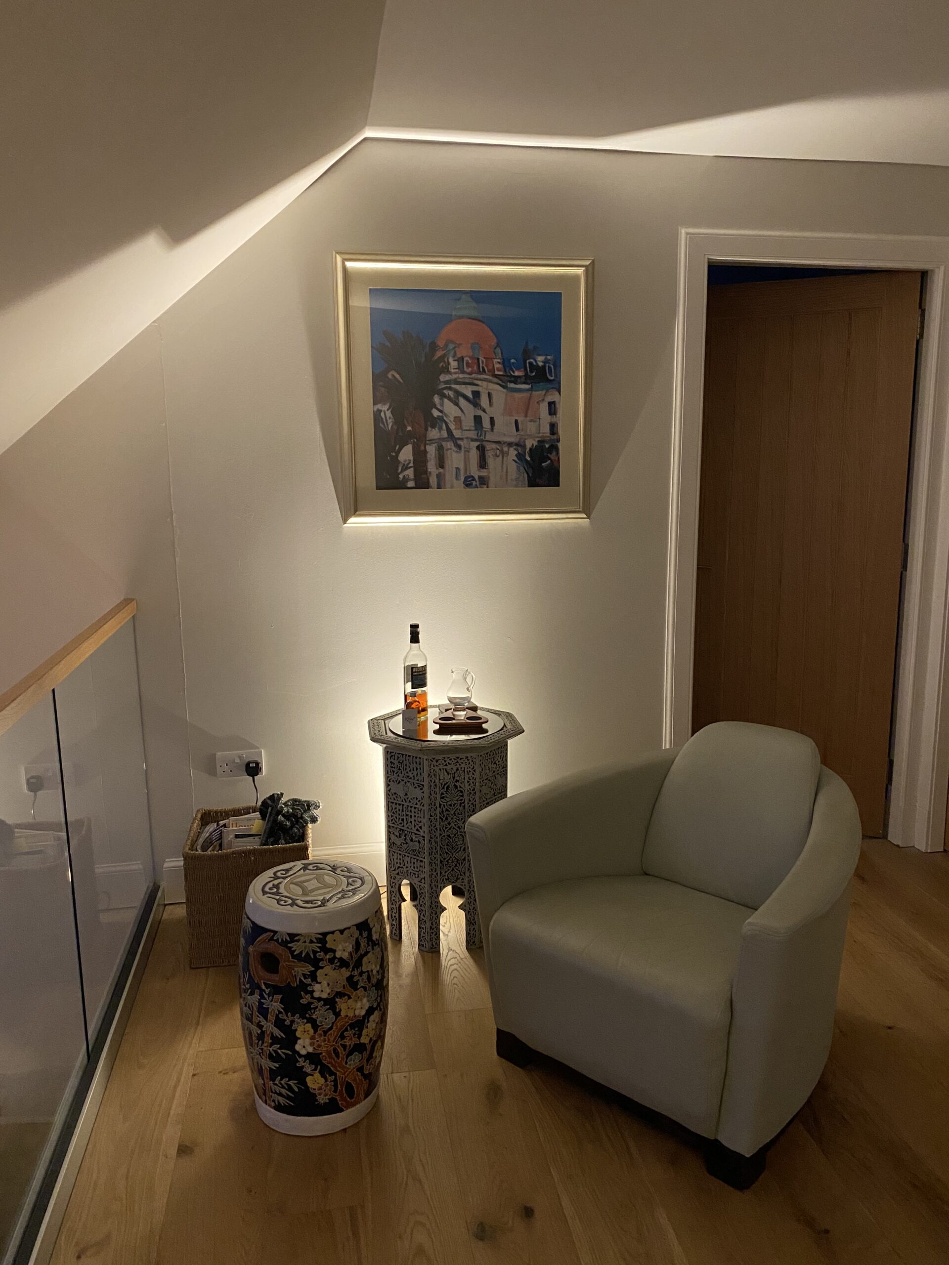 Top tips for cosy lighting in your home. A photo of a home interior with soft lighting and armchair designed by Cat Lighting, specialist lighting designer
